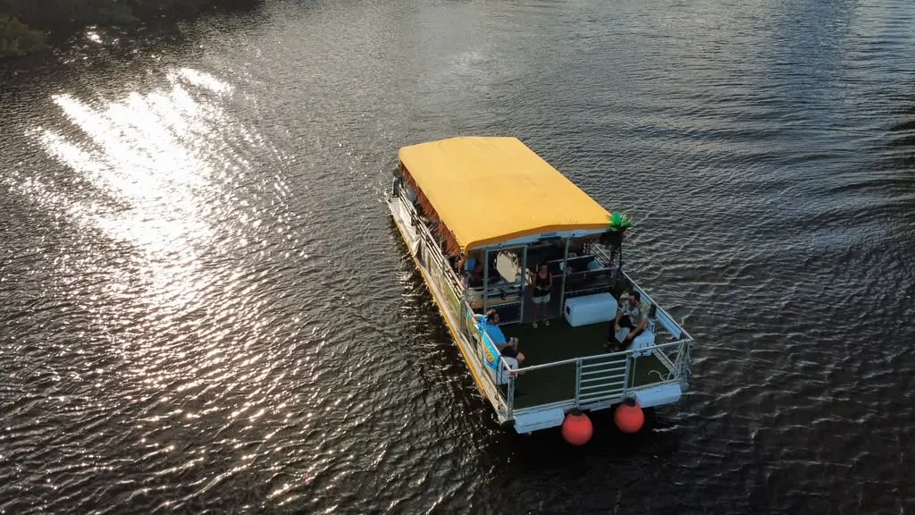 Drone shot of tiki boat with guests at golden hour on the river