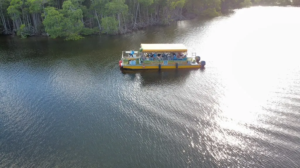 Aerial view of tiki boat on calm waters with sunlight reflecting off the river
