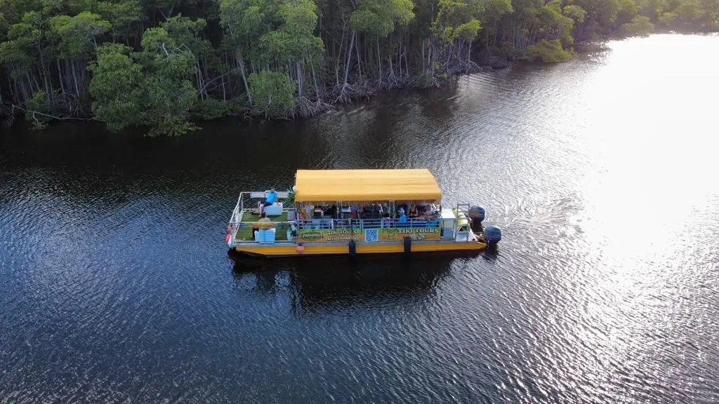 Tiki Paradiso with guests aboard cruising past mangrove shoreline